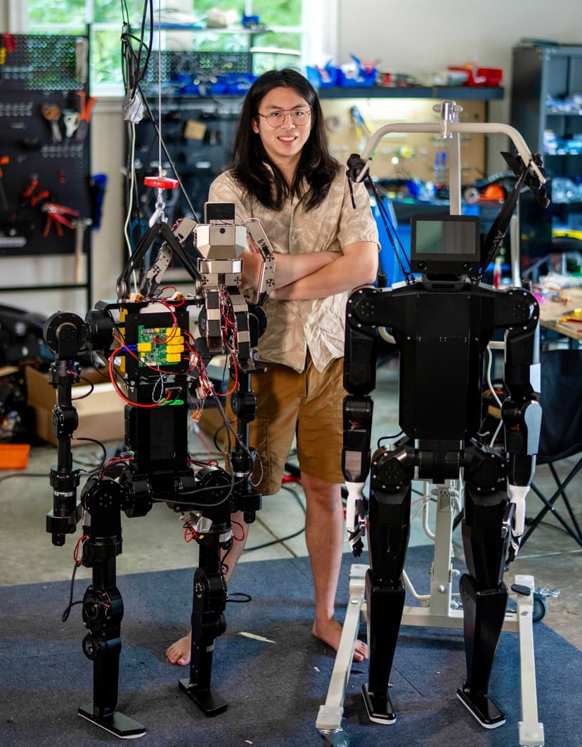 JX Mo standing with two humanoid robots in a workshop